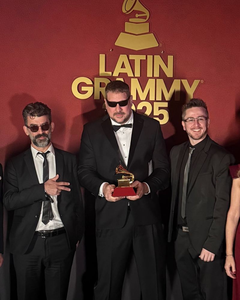 Tres integrantes de Tanghetto con la estatuilla del Latin GRAMMY frente al logo de la ceremonia