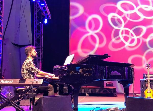 Antonio tocando un Steinway frente a una pantalla rosa